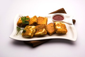 Amritsari Paneer Tikka made using cottage cheese cubes dipped in a batter made with besan, chat masala and spices and shallow fried in pan, served with ketchup