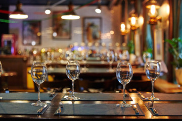 empty glass goblets glasses on a wooden table, next to forks