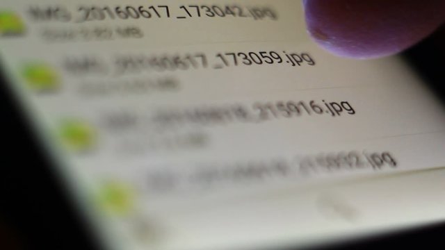 Close up, macro of sliding, searching, browsing jpg photos on a mobile phone.