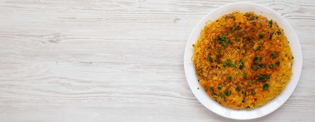 Homemade spaghetti omelette on a white plate over white wooden surface, top view. Flat lay, overhead, from above. Copy space.