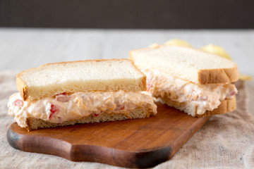 Delicious Homemade Pimento Cheese Sandwich with chips on a rustic wooden board, side view. Closeup.