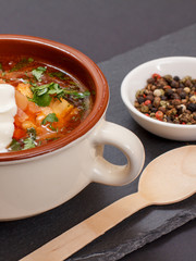 Ukrainian traditional borsch with wooden spoon on black background.