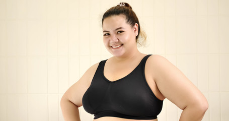 Happy chubby woman standing in the room.