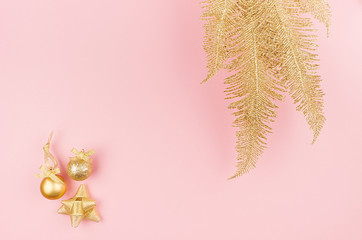 Christmas golden decorations as festive bright background - gold glittering branch and balls, ribbon on pastel pink color.