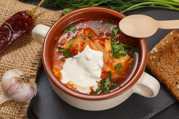 Ukrainian traditional borsch with wooden spoon on black background.