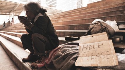 Homeless man sitting on stairs and eating food.