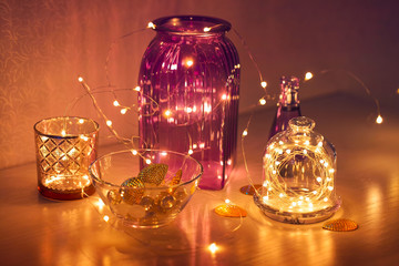 Fototapeta na wymiar Twinkling lights in the interior, festive garlands with glass vases, home cozy decor