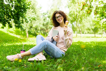 Naklejka na ściany i meble freelance concept. girl sitting on grass with laptop and ice cream