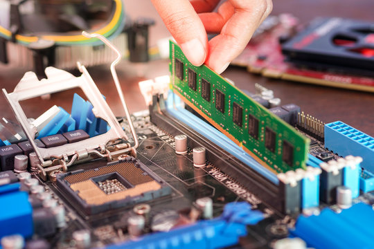 Engineers are placing the RAM on the sockets of the computer motherboard.