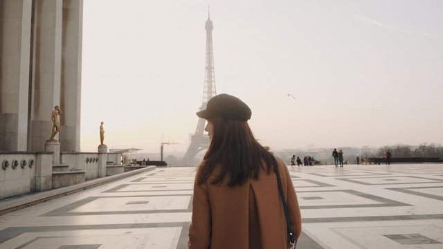 Happy beautiful tourist woman smiling, walking towards Eiffel Tower at Trocadero, Paris on romantic vacation slow motion