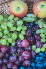 fresh juicy berries of red and white grapes on wicker wooden background