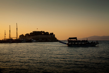 Obraz premium Kusadasi, Turkey - September 17, 2019: Castle on Pigeon Island in Kusadasi, Turkey. Historic Byzantine fortress on the sea. Boat trip during sunset.