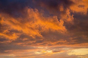 Naklejka na ściany i meble Orange dramatic cumulus clouds at sunset. Backlight