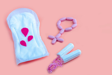Protective menstrual pad, cotton tampons and gender symbol made from pink pain pills. The concept of women gynecological health and intimate hygiene. Flat lay, copy space for text, close up