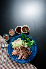 Traditional Thai food, Sliced grilled beef and organic vegetable salad with chili sauce thai style dressing on wooden plate have an appetizer dining in restaurant.