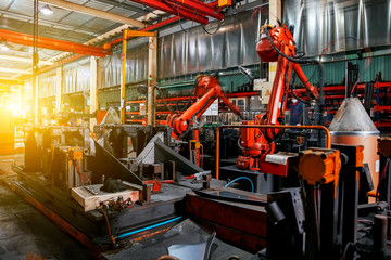 Large factory robotic arms are spraying sparks to weld car frames