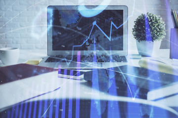 Stock market graph on background with desk and personal computer. Double exposure. Concept of financial analysis.