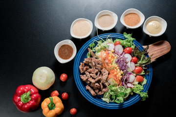 Traditional Italian food, Sliced grilled beef and organic vegetable salad with salad dressing on wooden plate have an appetizer dining in restaurant.