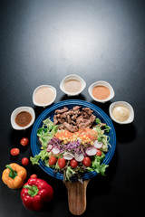 Traditional Italian food, Sliced grilled beef and organic vegetable salad with salad dressing on wooden plate have an appetizer dining in restaurant.