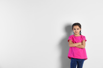 Portrait of cute little girl on light background, space for text