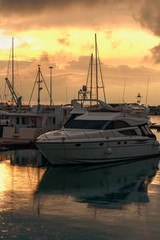 modern small boats and sailboats are parked in a quiet harbor in the seaport of Sochi on a rainy evening