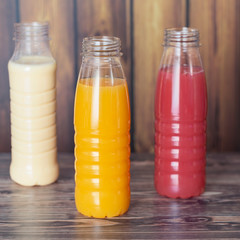 three bottles of milkshake on wooden wall background.