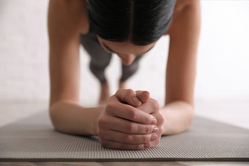 Young woman practicing forearm plank asana in yoga studio, closeup. Phalankasana pose variation