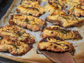 Baked red fish in a sauce with a sprig of rosemary and lemon on paper parchment