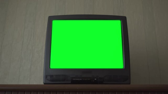 small TV-set with green electronic chromakey projection on screen locates on table in flat low angle shot