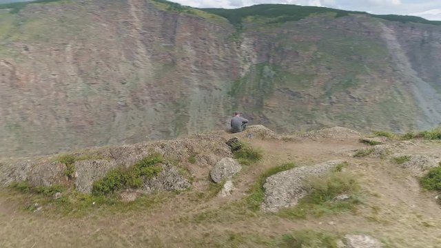 Drone fly around two young men sitting on edge of abyss near Katu-Yaryk pass