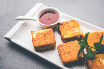 Amritsari Paneer Tikka made using cottage cheese cubes dipped in a batter made with besan, chat masala and spices and shallow fried in pan, served with ketchup