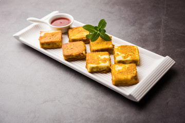 Amritsari Paneer Tikka made using cottage cheese cubes dipped in a batter made with besan, chat masala and spices and shallow fried in pan, served with ketchup