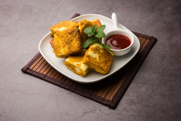 Amritsari Paneer Tikka made using cottage cheese cubes dipped in a batter made with besan, chat masala and spices and shallow fried in pan, served with ketchup