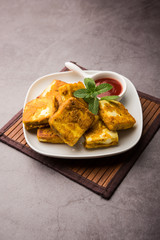 Amritsari Paneer Tikka made using cottage cheese cubes dipped in a batter made with besan, chat masala and spices and shallow fried in pan, served with ketchup
