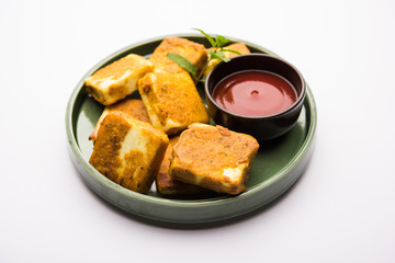 Amritsari Paneer Tikka made using cottage cheese cubes dipped in a batter made with besan, chat masala and spices and shallow fried in pan, served with ketchup
