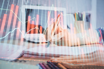 Financial forex charts displayed on woman's hand taking notes background. Concept of research. Double exposure