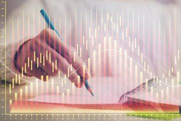 Financial forex graph displayed on hands taking notes background. Concept of research. Double exposure