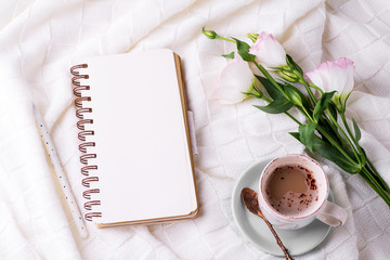 Having a cup of coffee , flowers eustoma and notebook on blanket in bed. Holiday concept