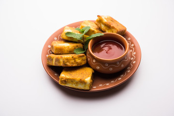 Amritsari Paneer Tikka made using cottage cheese cubes dipped in a batter made with besan, chat masala and spices and shallow fried in pan, served with ketchup