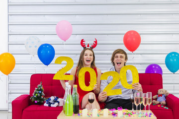 Cute Caucasian couple hold smartphone selfie while celebrate happy new year and Christmas day on red sofa