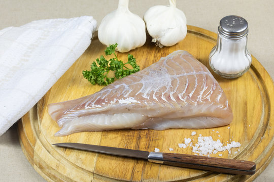 raw saithe fillet on a cutting board