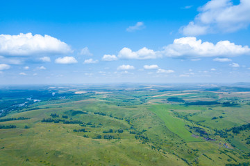 Landscape of green valley flooded with light with lush green grass, a fresh summer day under a blue sky with white clouds