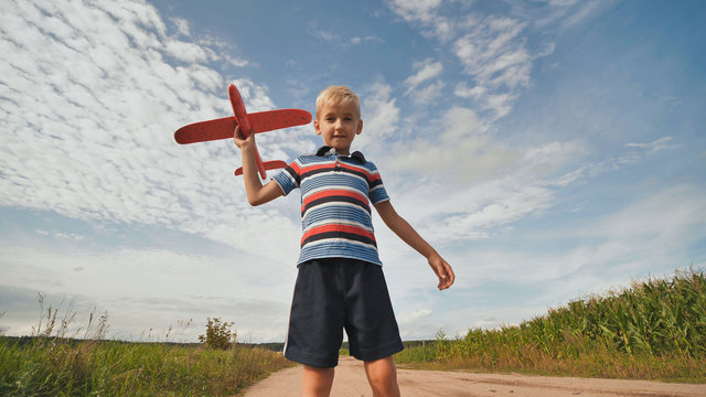 A little boy runs and launches a paralon toy airplane.