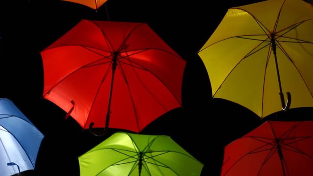 Vivid umbrellas at night, on the street, above on wires. Artistic installation,