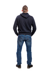 A young man in a hoodie and jeans stands with his back to the camera. Back view. Full height. Isolated over white background. Vertical.