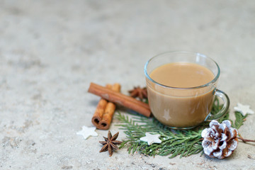 Cup of coffee, pine cone, cinnamon sticks and anise stars on a green branch of cypress. New Year's breakfast design. Selective focus, copy space