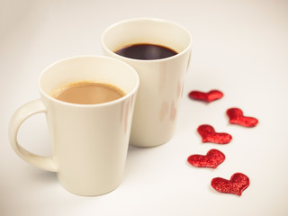 Two cup of coffee with 5 red glitter hearts decorated on white background
