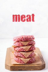 raw frozen minced meat patties on a wooden board, on a white background.