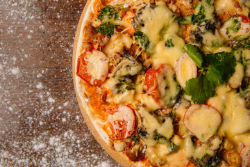 Hot big pizza pizza composition with melting cheese chicken tomatoes mushrooms steam smoke on a black background