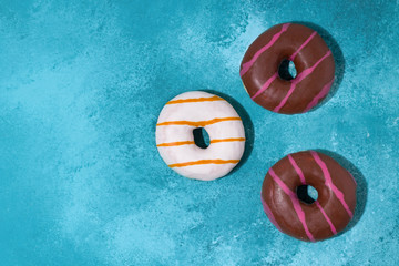 Donuts with white and chocolate icing on a blue background. copy space